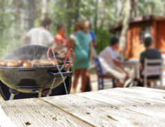 Food cooking on grill with family gathered in the background