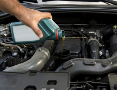A person pouring motor oil into a car